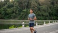 An athlete, strong Asian male runner in sportswear is running in a parl in the morning