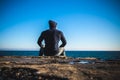 Athlete taking break sitting on rocks with sea horizon