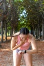 Athlete tired woman watching her smart watch in a park. Sporty young woman watching the clock in a park.