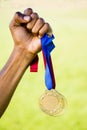 Athletes hand holding gold medal after victory