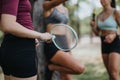 Athletes resting after training outdoors, holding rackets and a ball. Happy girls enjoying a conversation in a park on a Royalty Free Stock Photo