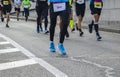 Athletes running urban marathon race on autumn road. Closeup on people feet