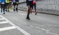 Athletes running urban marathon race on autumn road. Closeup on people feet