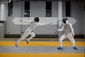 Athletes in uniforms and protective helmet mask fighting duel with rapiers