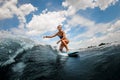 Athletic and active woman riding on wave sitting on surfboard against blue sky Royalty Free Stock Photo