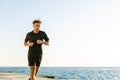 athletic adult joger running on seashore