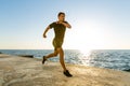 athletic adult man jogging on seashore in front