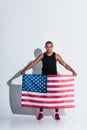 athletic african american sportsman holding american flag and looking at camera
