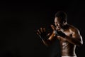 Athletic african fighter on black background. Dark skinned undressed man shows a fight. Advert for sport club and gym