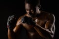 Athletic african fighter on black background. Dark skinned undressed man shows a fight. Advert for sport club and gym