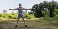 An athletic asian guy does jumping jacks at a open field near the city. Cardiovascular fitness. Working out outdoors