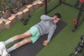 An athletic asian man does oblique crunches while lying on a black mat. Leg raised for added challenge. Working out his midsection Royalty Free Stock Photo