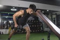 An athletic asian man does one-arm dumbbell rows while leaning on an incline bench. Performing negative reps. Back exercise