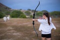 Athletic and athletic girl aiming a bow and arrow at an archery range. Royalty Free Stock Photo