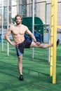 Athletic bearded man with muscular body stretching on outdoor stadium