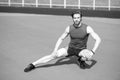 Athletic bearded man with muscular body stretching on running track