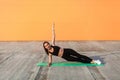 Athletic beautiful girl in tight sportswear, black pants and top, practicing yoga, doing Vasisthasana side plank pose Royalty Free Stock Photo