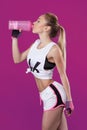 Athletic beautiful young blond woman drinks gainer