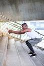 Athletic Black American men in a sport wear are exercising outdoors by doing squats.