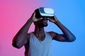 Athletic black guy wearing VR headset, doing virtual workout in augmented reality, neon lighting Royalty Free Stock Photo