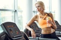 Athletic blond woman with bottle of water on treadmill in gym. Royalty Free Stock Photo