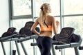 Athletic blond woman running on treadmill at gym.