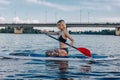 athletic blonde girl sitting on sup board