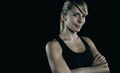 Athletic blonde woman with arms crossed over dark