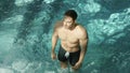 Athletic body man diving in swimming pool. Sexy hipster guy standing whirlpool.