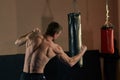 Athletic boxer throwing a fierce and powerful punch. Photo of muscular man in gym.