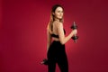 Athletic brunette girl in a black top with dumbbells, posing on a red cherry background. Back view Royalty Free Stock Photo