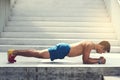 Athletic build man doing plank near stairs
