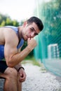 Athletic caucasian man sitting on bench and looking at camera
