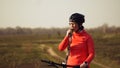 Athletic Caucasian woman eats protein bar ride on mountain bike on nature. Young sporty woman athlete in helmet resting while