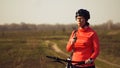 Athletic Caucasian woman eats protein bar ride on mountain bike on nature. Young sporty woman athlete in helmet resting while Royalty Free Stock Photo