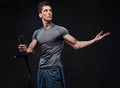 Athletic male holds barbell over grey background.