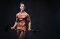 Athletic male holds barbell over grey background.