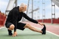 Athletic elderly sportsman strecthing legs, have outdoor workout Royalty Free Stock Photo