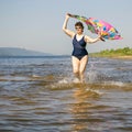 Athletic elderly woman runs along the waves on a summer sunny day against the background of mountains Royalty Free Stock Photo