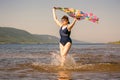 Athletic elderly woman runs along the waves on a summer sunny day against the background of mountains Royalty Free Stock Photo