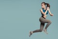 Athletic energetic girl jumping on blue background