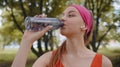 Athletic fit sport jogger young woman drinking water from bottle after training exercising in park Royalty Free Stock Photo