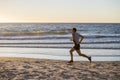 Athletic fit and strong runner man training on Summer sunset beach in sea shore running and fitness workout in sport and healthy l Royalty Free Stock Photo