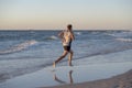 Athletic fit and strong runner man training on Summer sunset beach in sea shore running and fitness workout in sport and healthy l Royalty Free Stock Photo