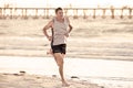 Athletic fit and strong runner man training on Summer sunset beach in sea shore running and fitness workout in sport and healthy l Royalty Free Stock Photo