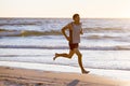 Athletic fit and strong runner man training on Summer sunset beach in sea shore running and fitness workout in sport and healthy l