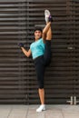 Athletic flexible young woman doing standing split exercise on the city street