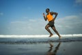 Athletic full body portrait of young attractive and fit black African American man running on the beach doing Summer fitness Royalty Free Stock Photo