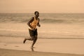 Athletic full body portrait of young attractive and fit black afro American man running on the beach doing Summer fitness jogging Royalty Free Stock Photo