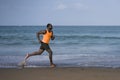 Athletic full body portrait of young attractive and fit black afro American man running on the beach doing Summer fitness jogging Royalty Free Stock Photo